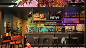 Zona de bar con taburetes, una guitarra y un letrero de neón.