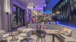Un área de estar moderna con disposición de asientos, un bar y un amplio ventanal con vistas al exterior.