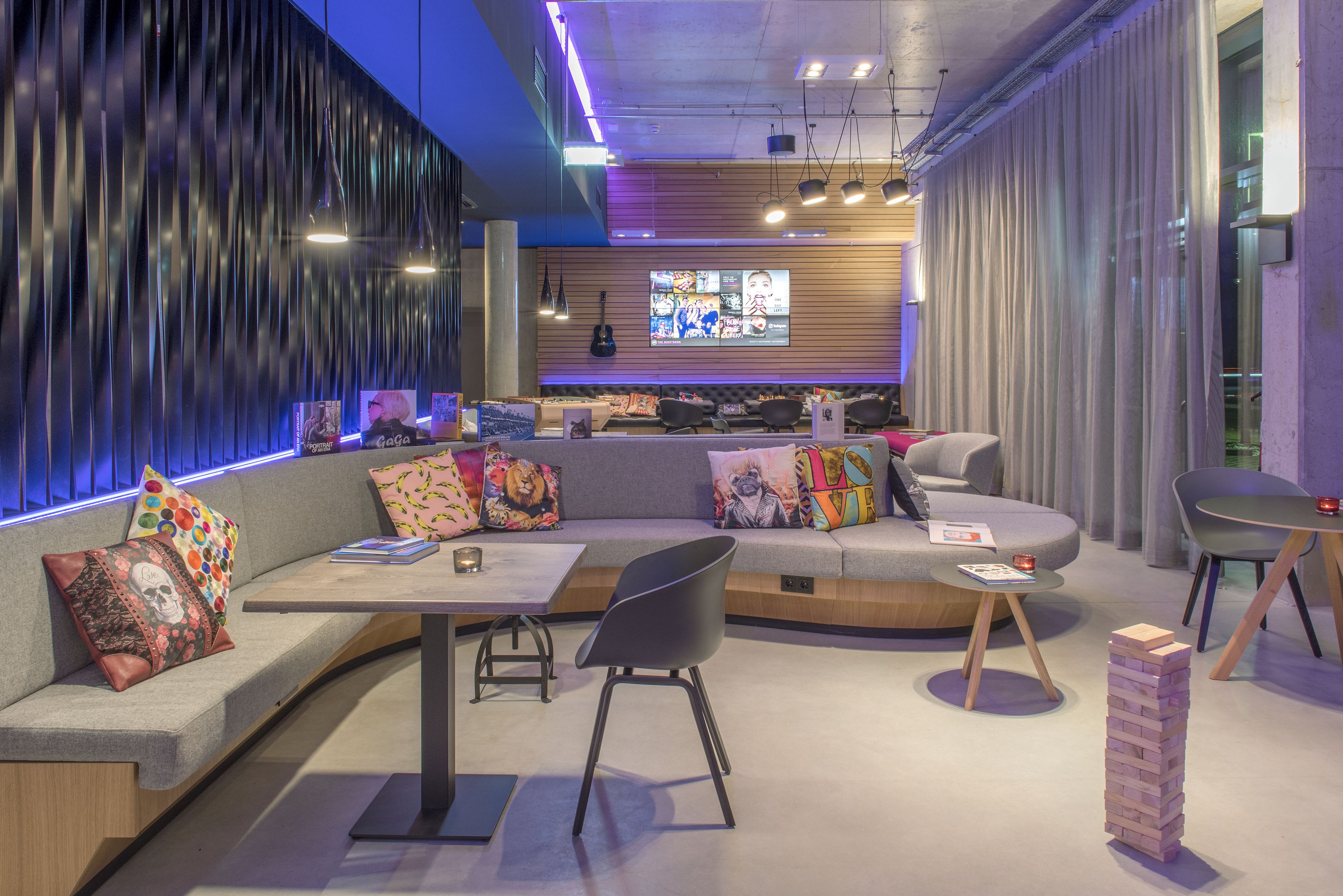 A modern lounge area with a curved sofa, a small table, and a stack of books.