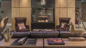 Una sala de estar moderna con chimenea, sofás de cuero y una escultura de ciervo montada en la pared.