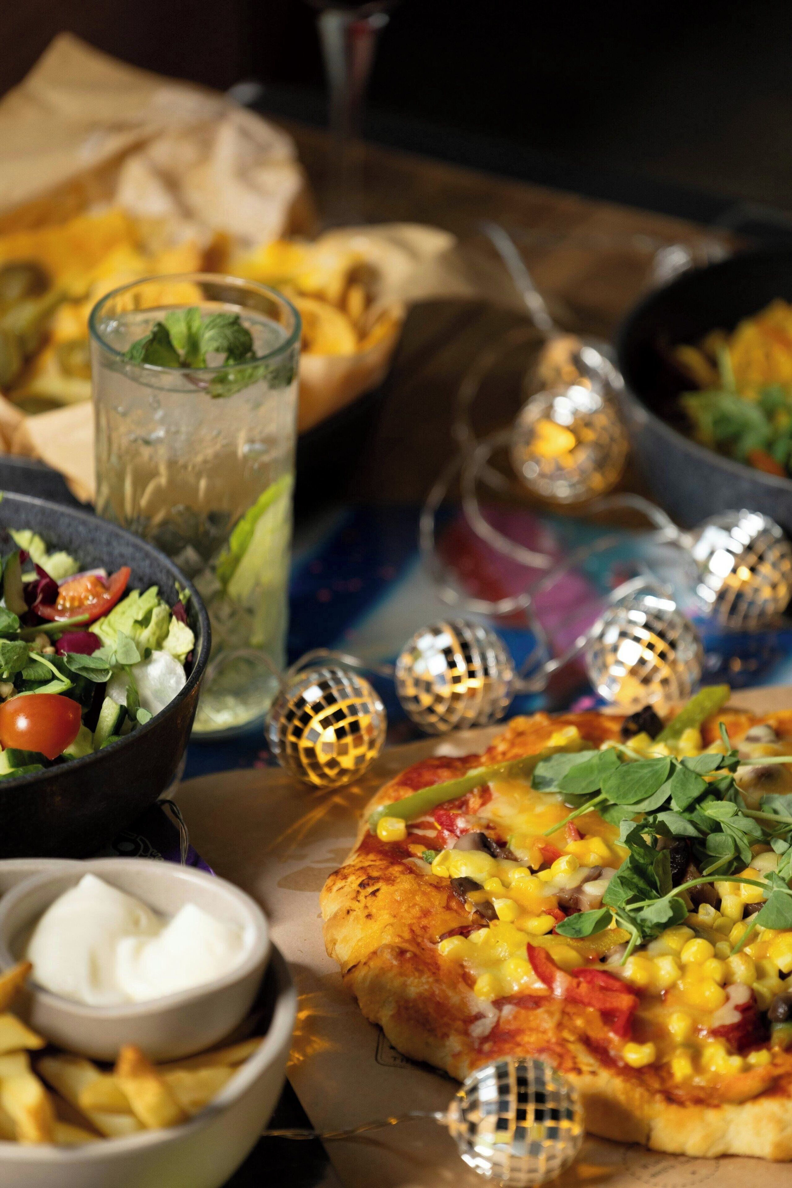A table with a pizza, salad, and drinks.