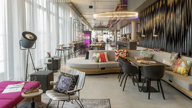 Un moderno vestíbulo de hotel con una zona de estar, un bar y un espacio para comer.