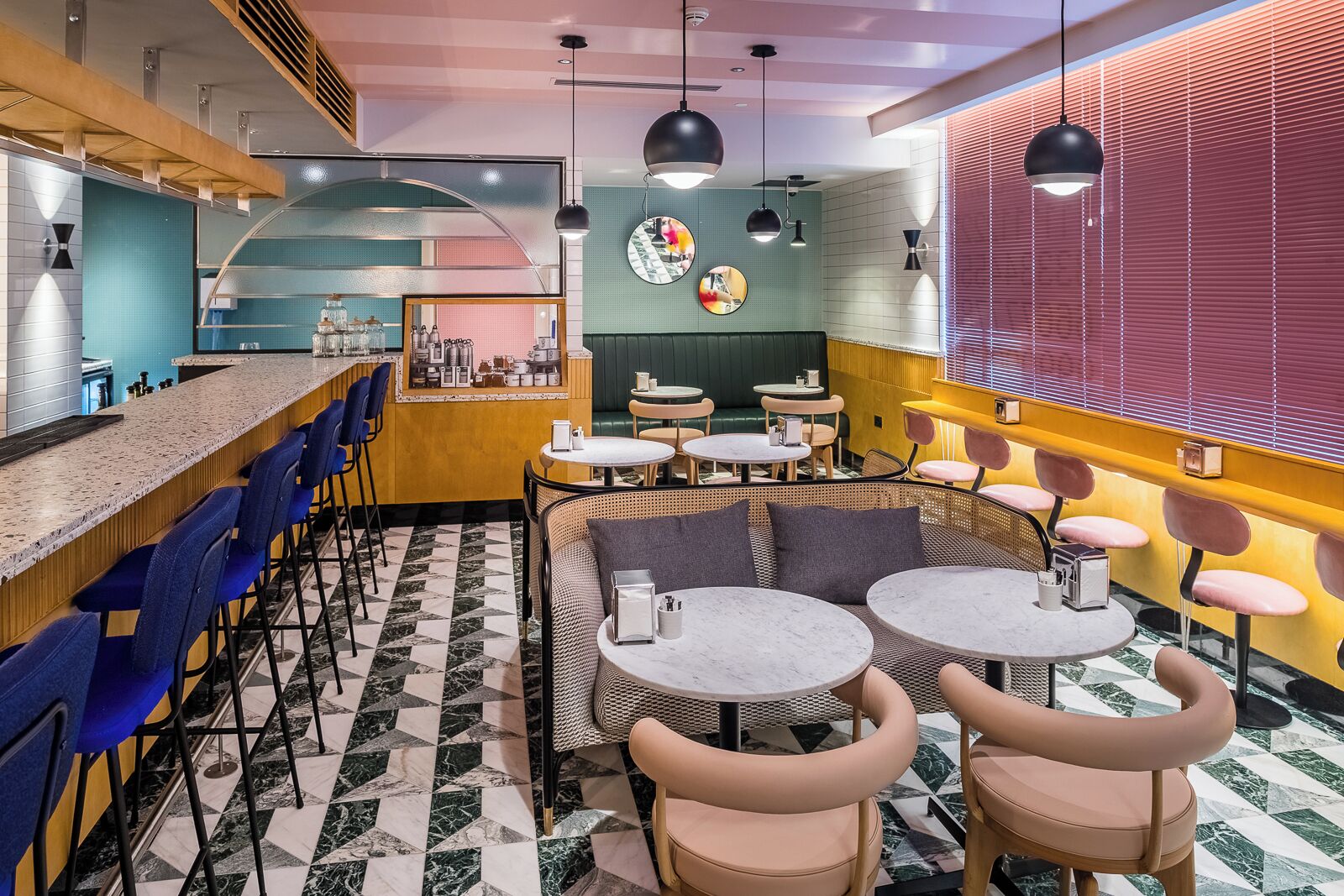 A modern cafe with bar seating, round tables, and a mix of blue and yellow decor.