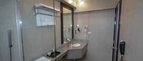 A modern bathroom with a glass shower enclosure, a granite countertop sink, and a handheld phone.