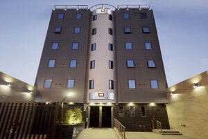 Un hotel moderno con una torre cilíndrica central, múltiples ventanales y un letrero que indica que es un hotel.