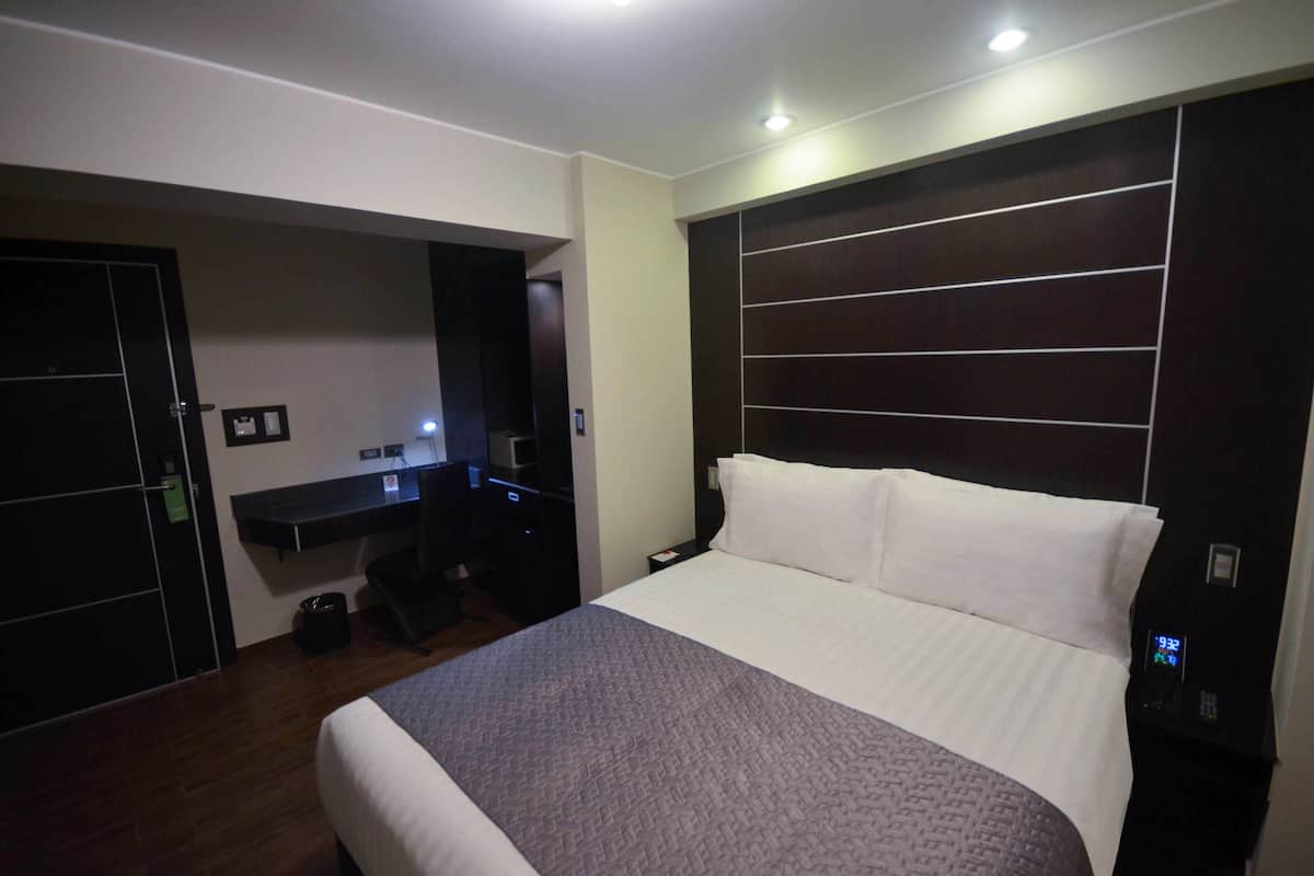Ein Hotelzimmer mit einem großen Bett, einem Schreibtisch mit Computer und einem Kleiderschrank.