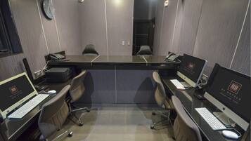 A conference room with a long table, four chairs, and four desktop computers.