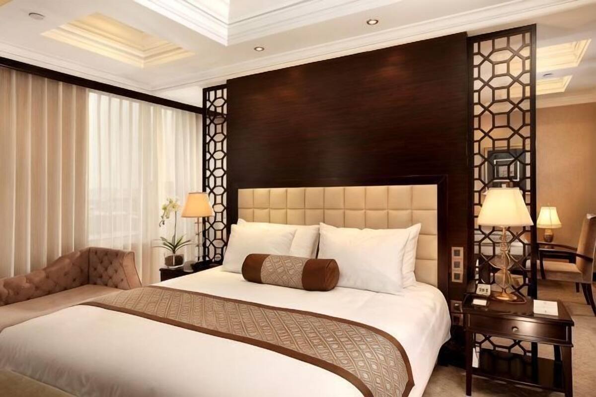 A large bed with a headboard, bedside tables, and lamps.
