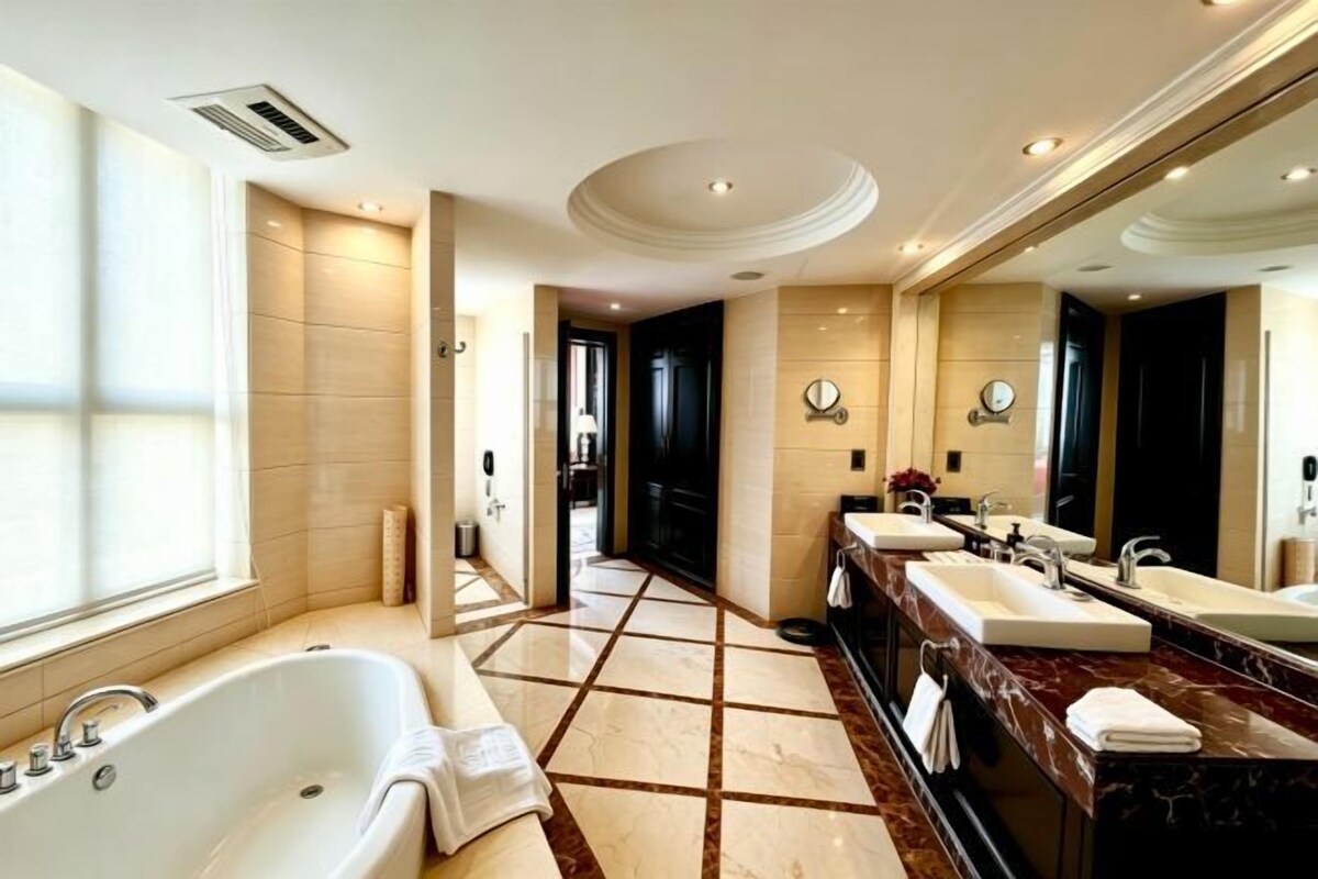 A spacious bathroom with a large bathtub, two sinks, and a mirror.