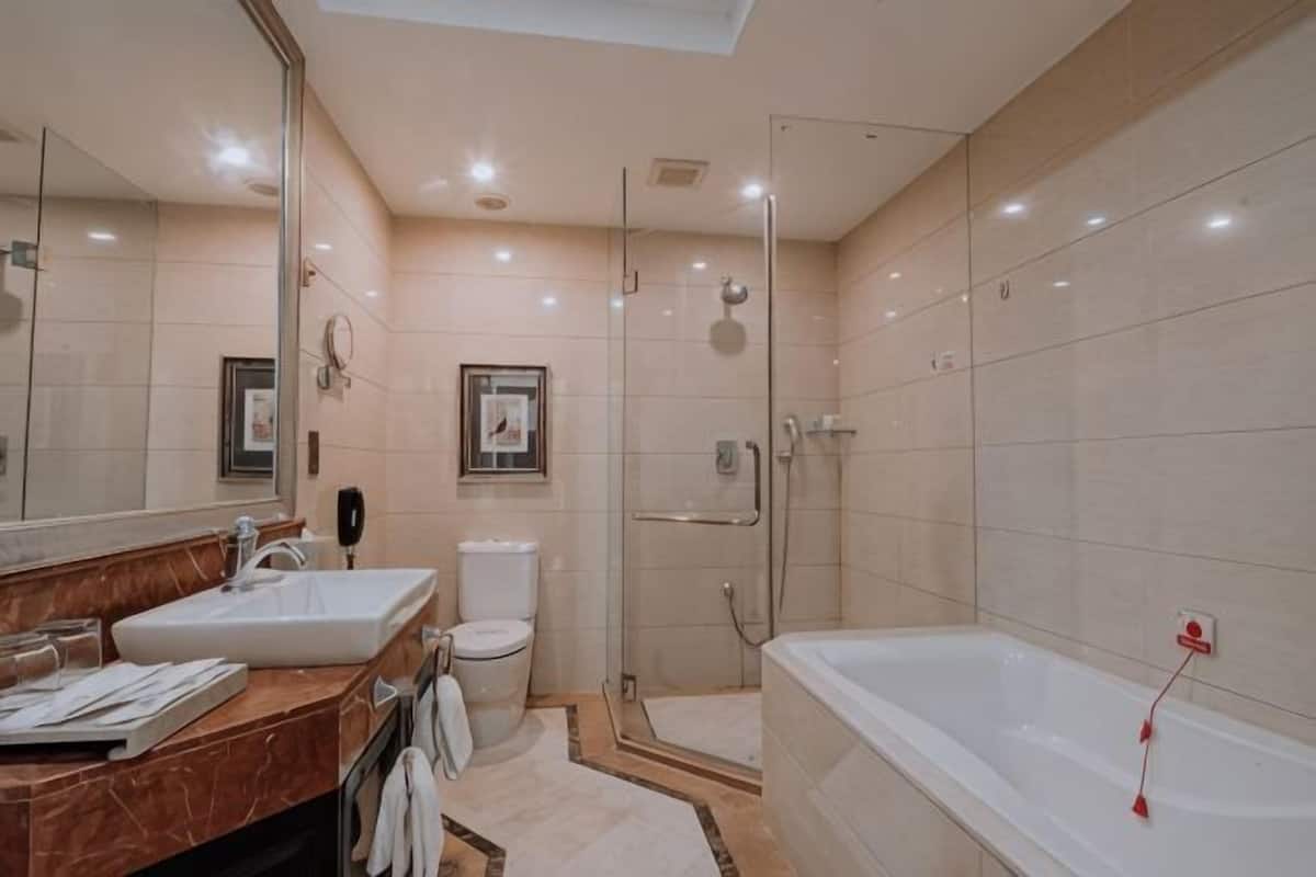 A modern bathroom with a large mirror, a bathtub, and a shower.