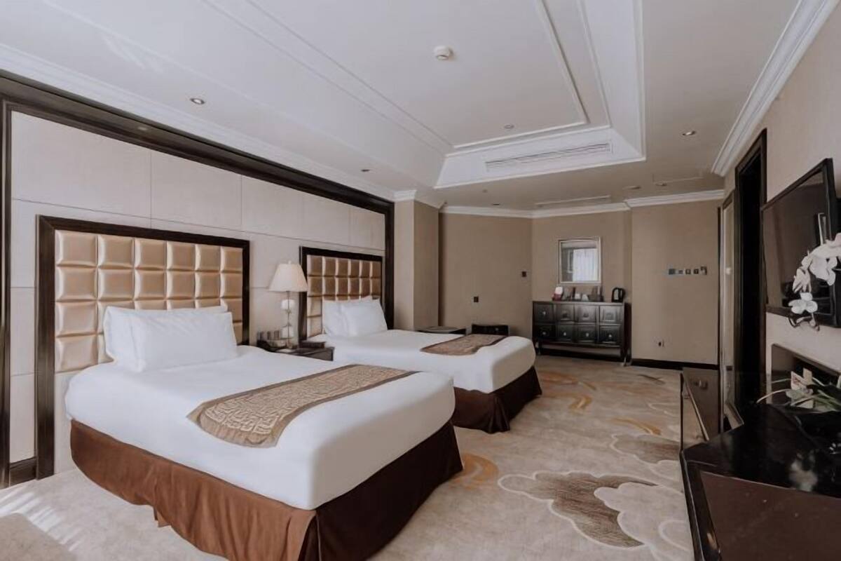 A hotel room with two beds, a television, a desk, and a mirror.