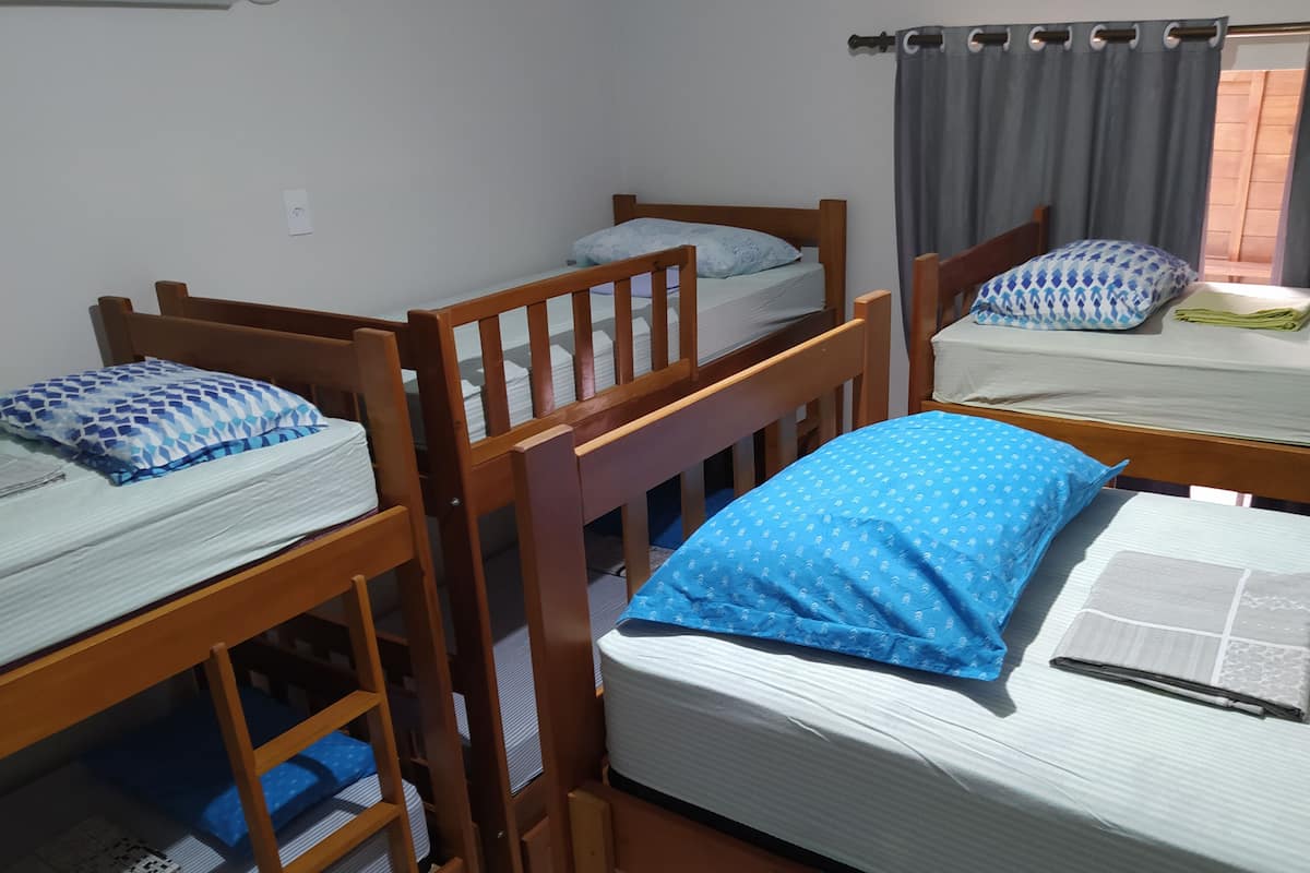 A dormitory room with bunk beds, a window with curtains, and a small table with a towel.
