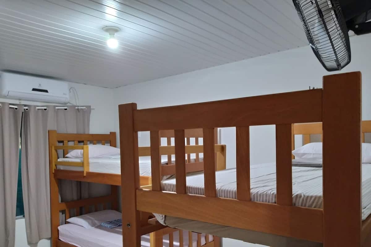 A dormitory room with bunk beds, a ceiling fan, and an air conditioning unit.