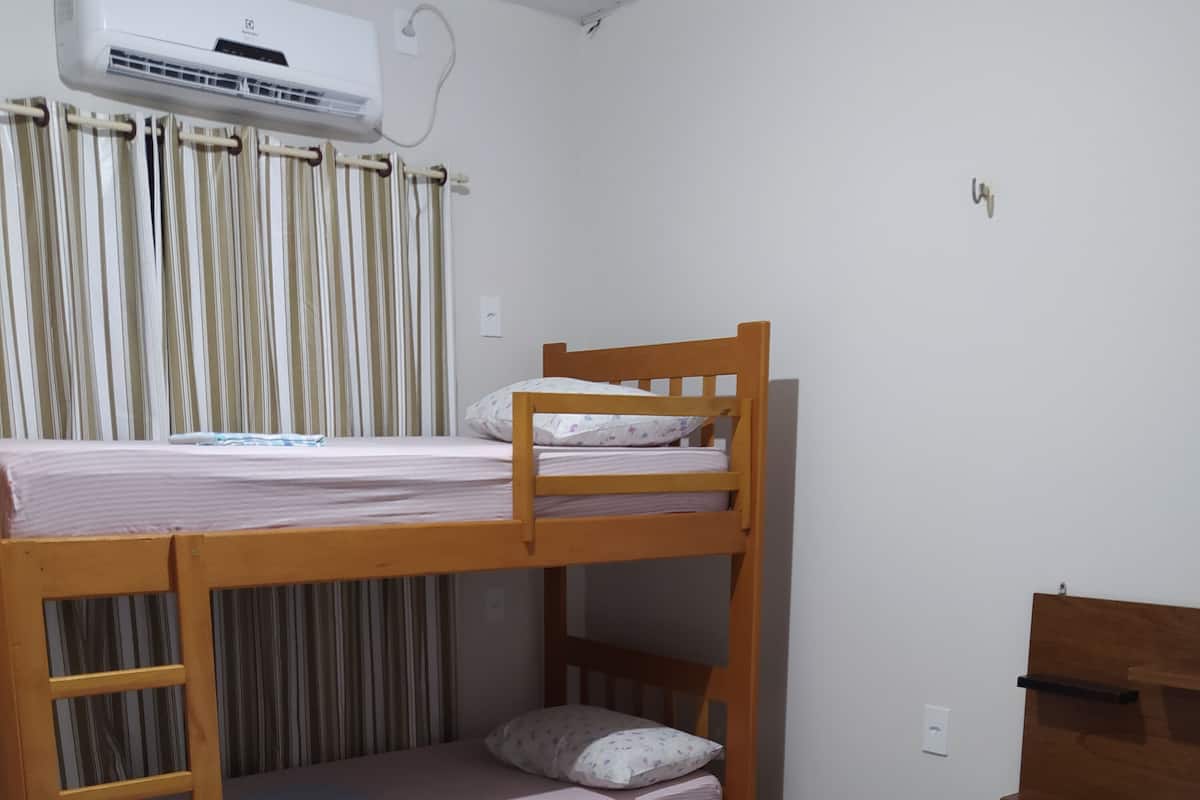 A bunk bed with a wooden frame, a small desk, and a white table.