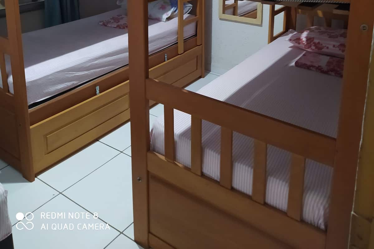 A room with bunk beds, a window with curtains, and an air conditioning unit on the wall.