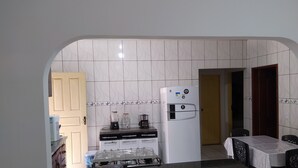 A compact kitchen with a refrigerator, a coffee maker, and a gas stove. - Hostel Lençóis Park (Barreirinhas)
