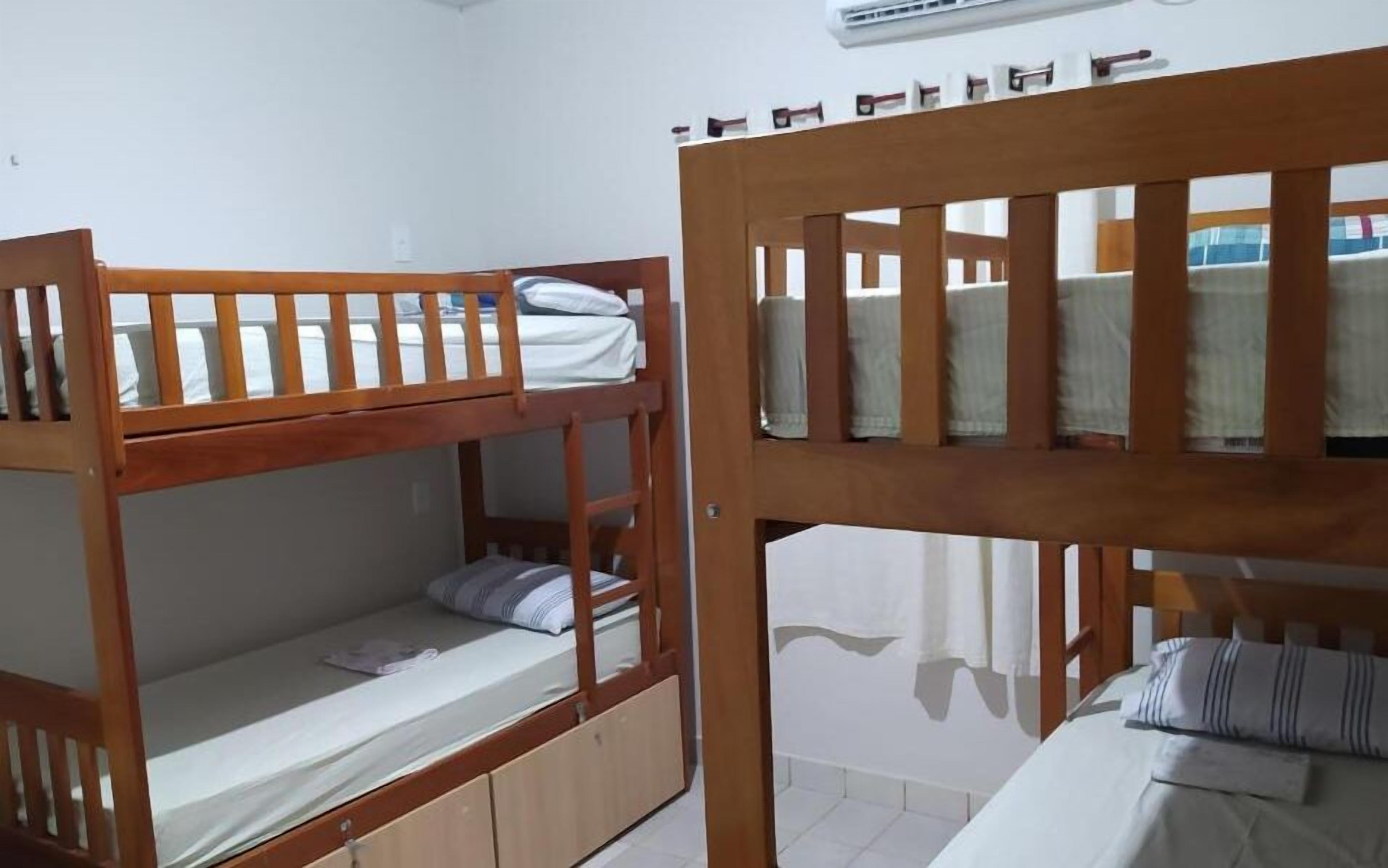 A room with two bunk beds, a small cabinet, and a window with curtains.