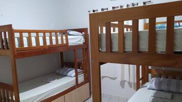 A room with two bunk beds, a small cabinet, and a window with curtains.