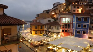 A bustling outdoor market with various stalls and tables under umbrellas, surrounded by colorful buildings with balconies. - LA Nana DEL MAR Flat on the old Port of Cudillero (Cudillero)