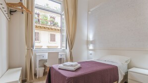 A bedroom with a bed, a desk, and a window with curtains. - Walker Rooms (Rome)