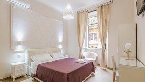 A bedroom with a bed, bedside table, chair, and a mirror. - Walker Rooms (Rome)