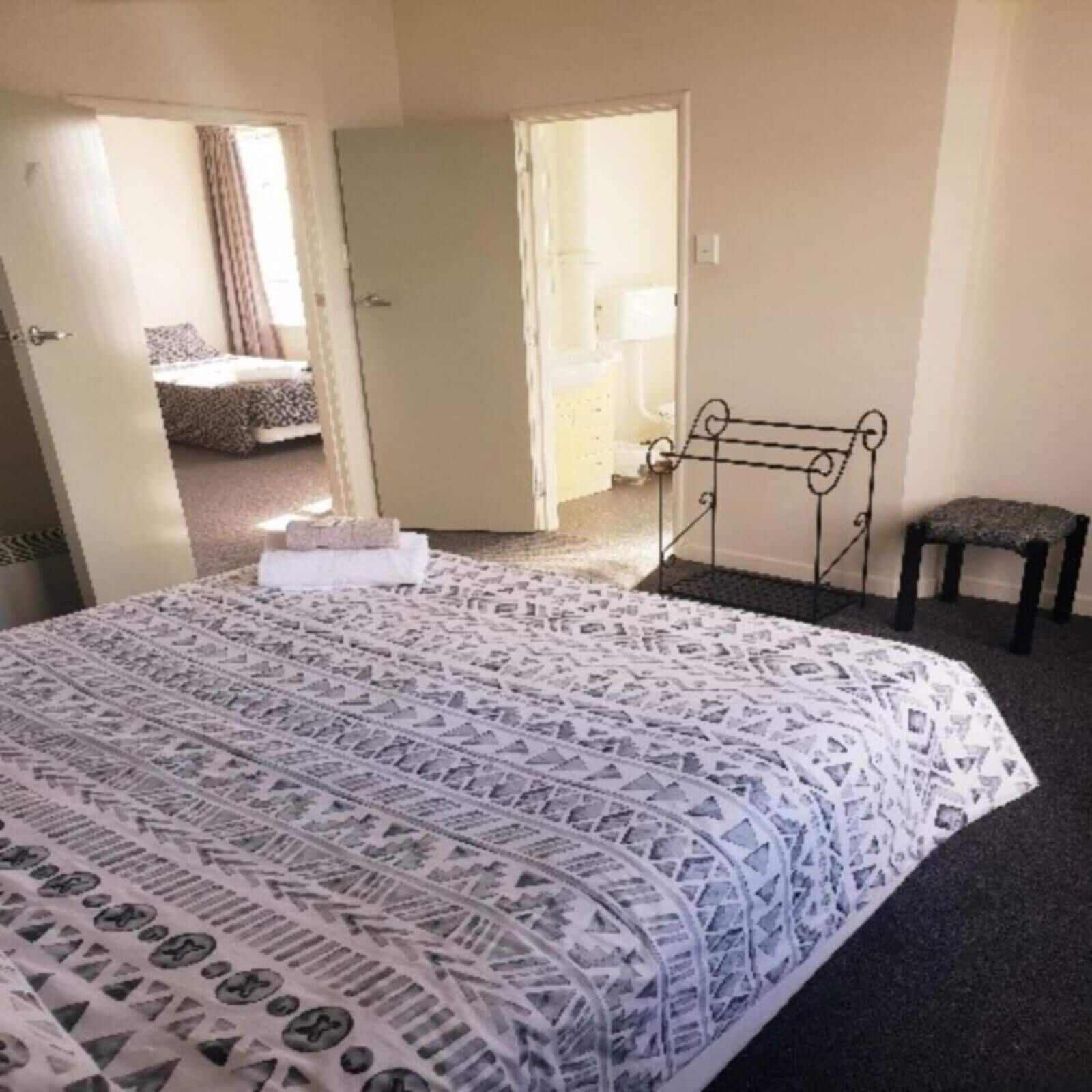 Ein Schlafzimmer mit einem gestreiften Bettbezug, einem kleinen Nachttisch und einem Sessel.