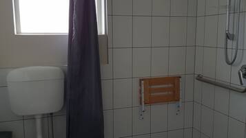 Ein Badezimmer mit Toilette, Dusche und Fenster.