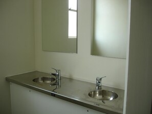 A bathroom with two stainless steel sinks and a mirror above them. - Horse and Jockey Inn (Matamata)