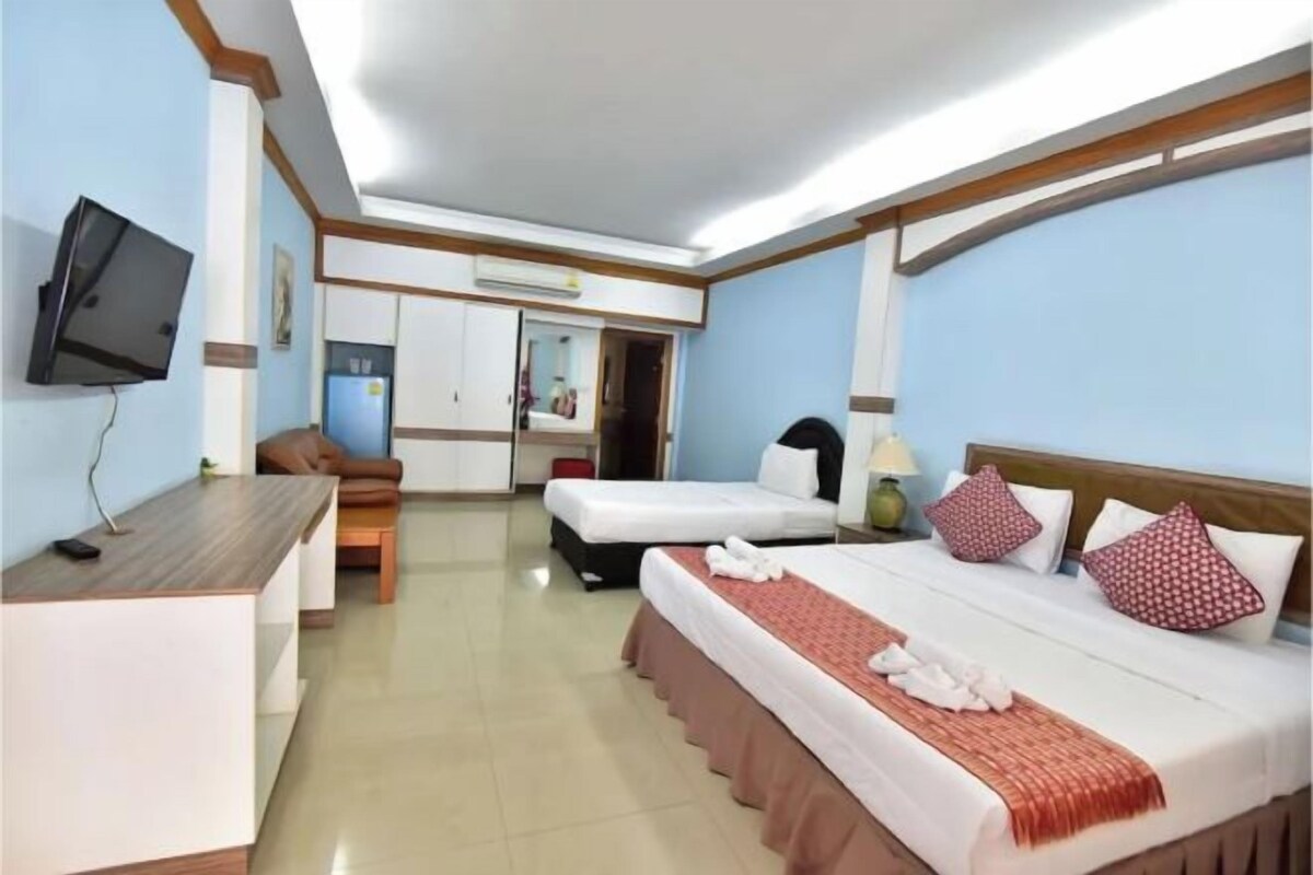 A hotel room with a bed, a desk, a chair, and a television.