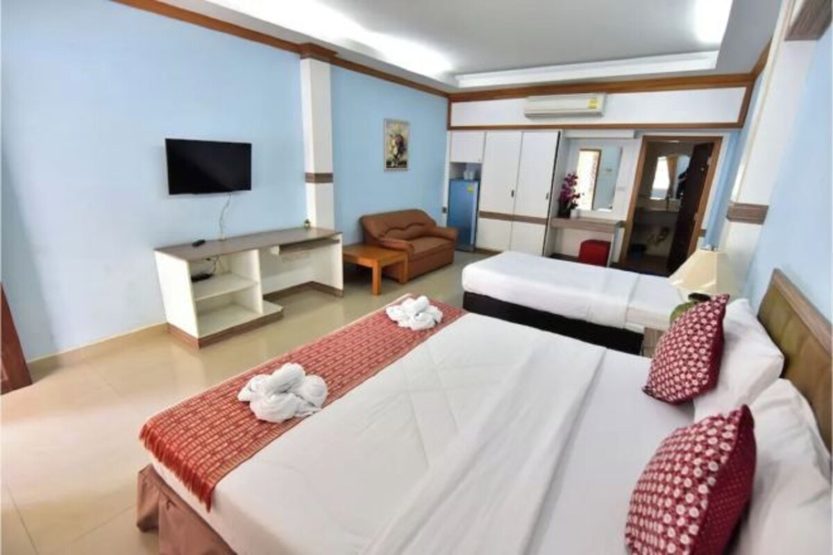 A hotel room with two beds, a desk, a TV, and a wardrobe.