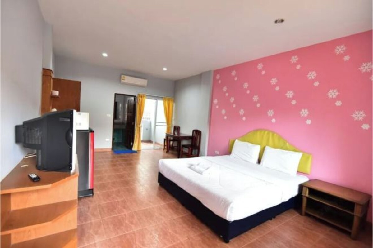 A hotel room with a bed, a desk with a computer, and a TV.