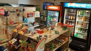 A convenience store with shelves stocked with snacks, beverages, and a 'Treat Yourself' sign.
