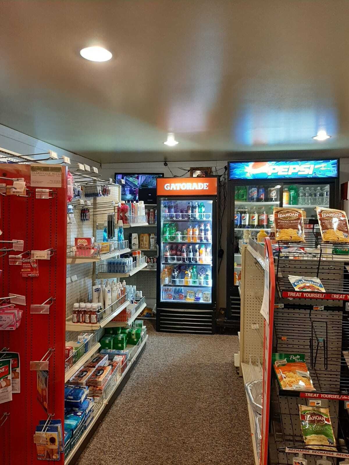 A grocery store aisle with Gatorade and Pepsi refrigerators, snack shelves, and a variety of packaged goods.