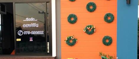 A building facade with a blue and orange color scheme, featuring decorative wreaths and a small garden area with statues.