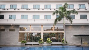 A hotel with a swimming pool, large windows, and a palm tree. - Novena Hotel (Lembang)