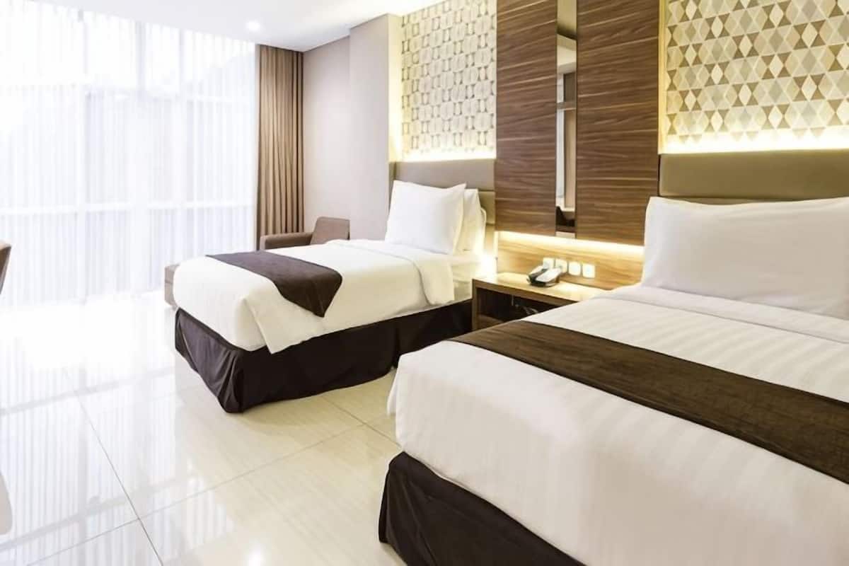 A hotel room with two beds, a desk, a chair, a phone, and a window with curtains.