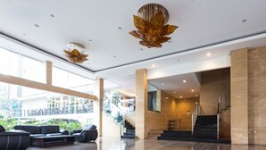 A spacious lobby with a modern design, featuring a staircase, seating area, and large windows. - Novena Hotel (Lembang)