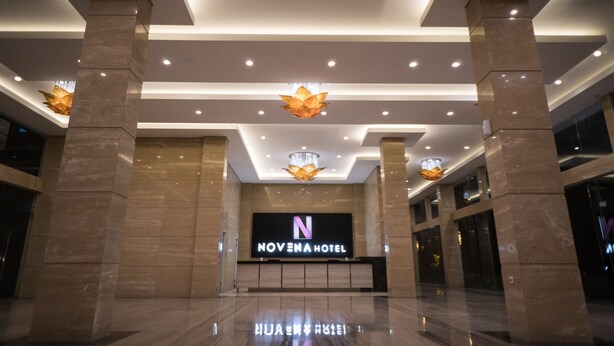 The Novena Hotel's entrance with a modern design, featuring a large illuminated sign, marble columns, and contemporary lighting fixtures. - Novena Hotel (Lembang)