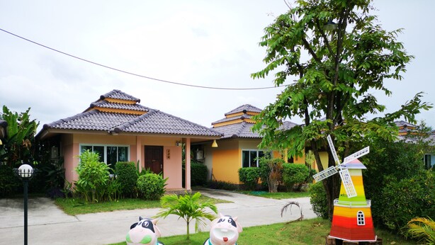 A traditional house with a tiled roof, surrounded by lush greenery and a windmill. - Terra Villa Resort (Chok Chai)