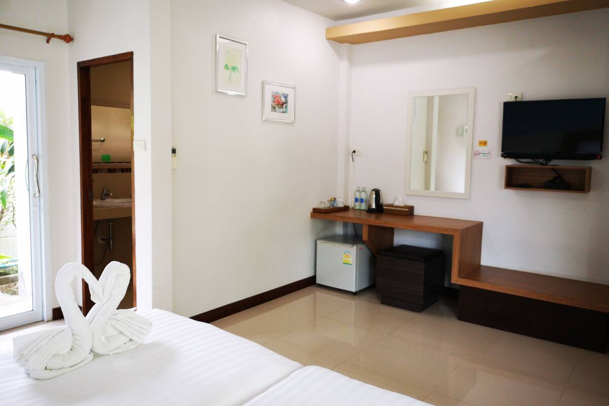 Ein Hotelzimmer mit Bett, Fernseher, kleinem Kühlschrank und angrenzendem Badezimmer.