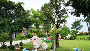 A garden with various animal sculptures, a small pond, and a house in the background. - Terra Villa Resort (Chok Chai)