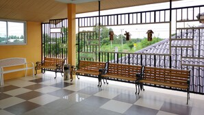 A waiting area with checkered flooring, benches, and a window with metal bars. - Terra Villa Resort (Chok Chai)