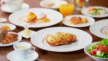 Desayuno con platos de comida, incluyendo cruasanes, huevos y una ensalada.
