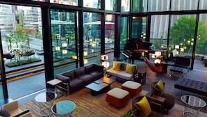 A modern lounge with a city view, featuring sofas, tables, and a piano. - The Gate Hotel Tokyo By HULIC (Tokyo)