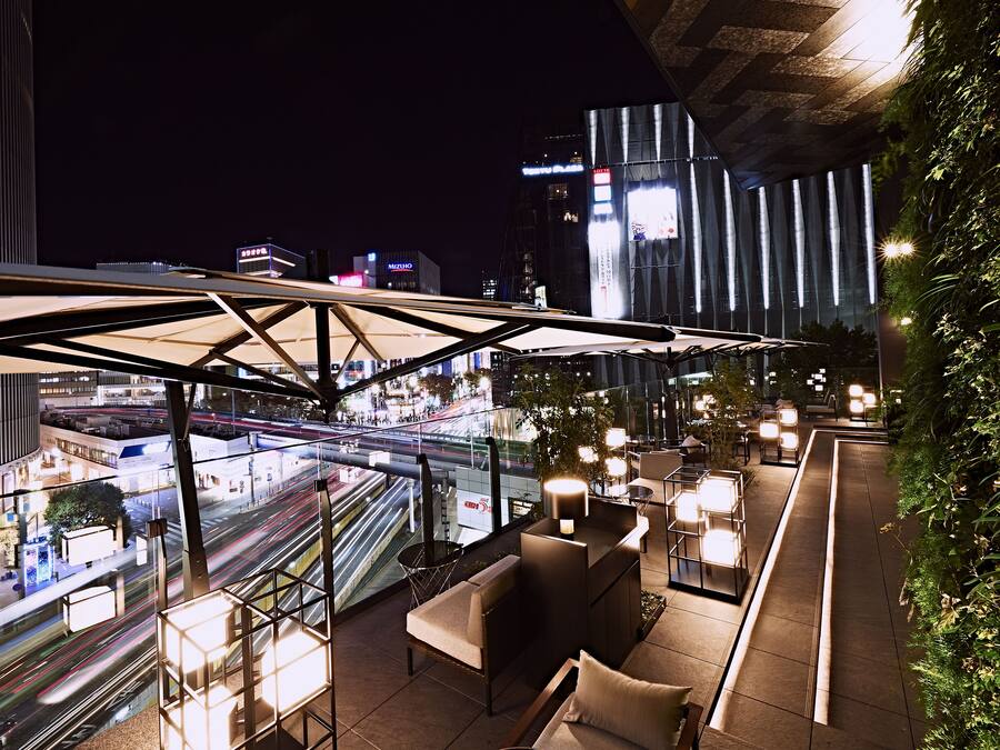 A rooftop bar with seating and a view of the cityscape at night.