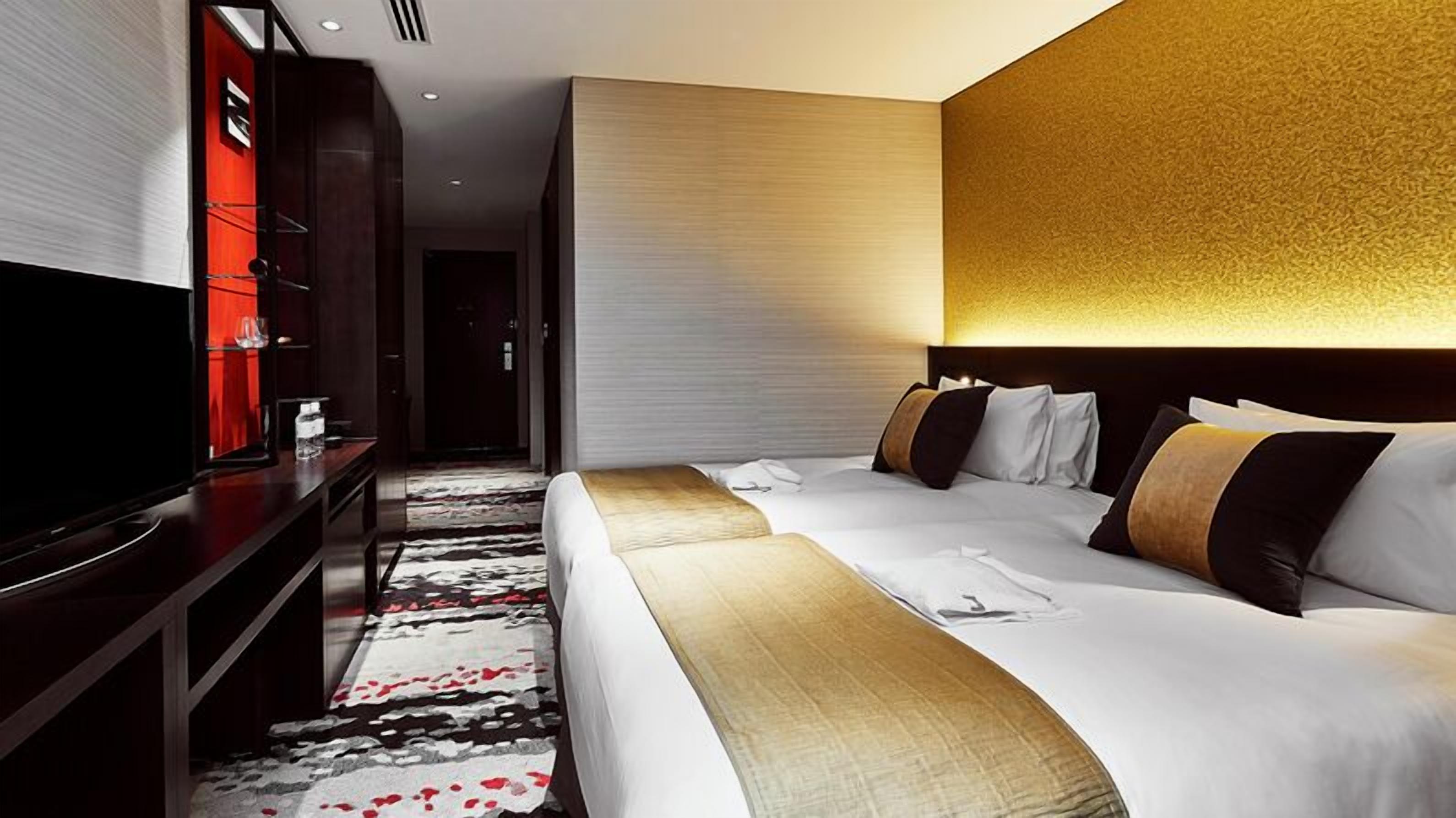 Ein Hotelzimmer mit einem großen Bett, einem Fernseher, einem Schreibtisch und einem Teppichboden.