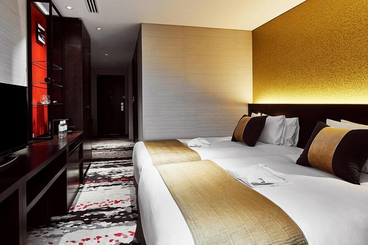 A hotel room with a large bed, a TV, a desk, and a carpeted floor.
