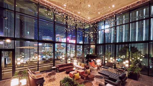 A spacious indoor area with large windows, modern furniture, and a piano. - The Gate Hotel Tokyo By HULIC (Tokyo)