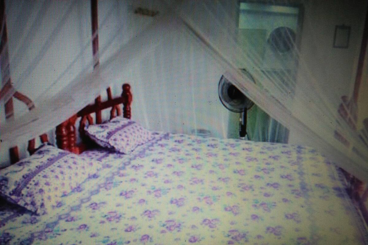 A bed with a patterned bedspread and a wooden headboard.