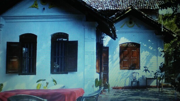 A white house with a tiled roof, a red table, and a bicycle. - White House (Unawatuna)